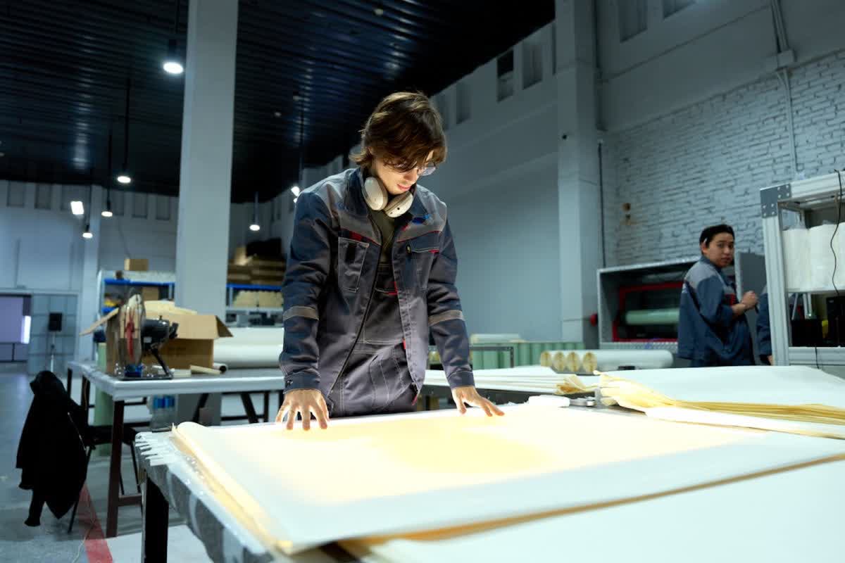 Factory inspector checking material sheets under inspection lights